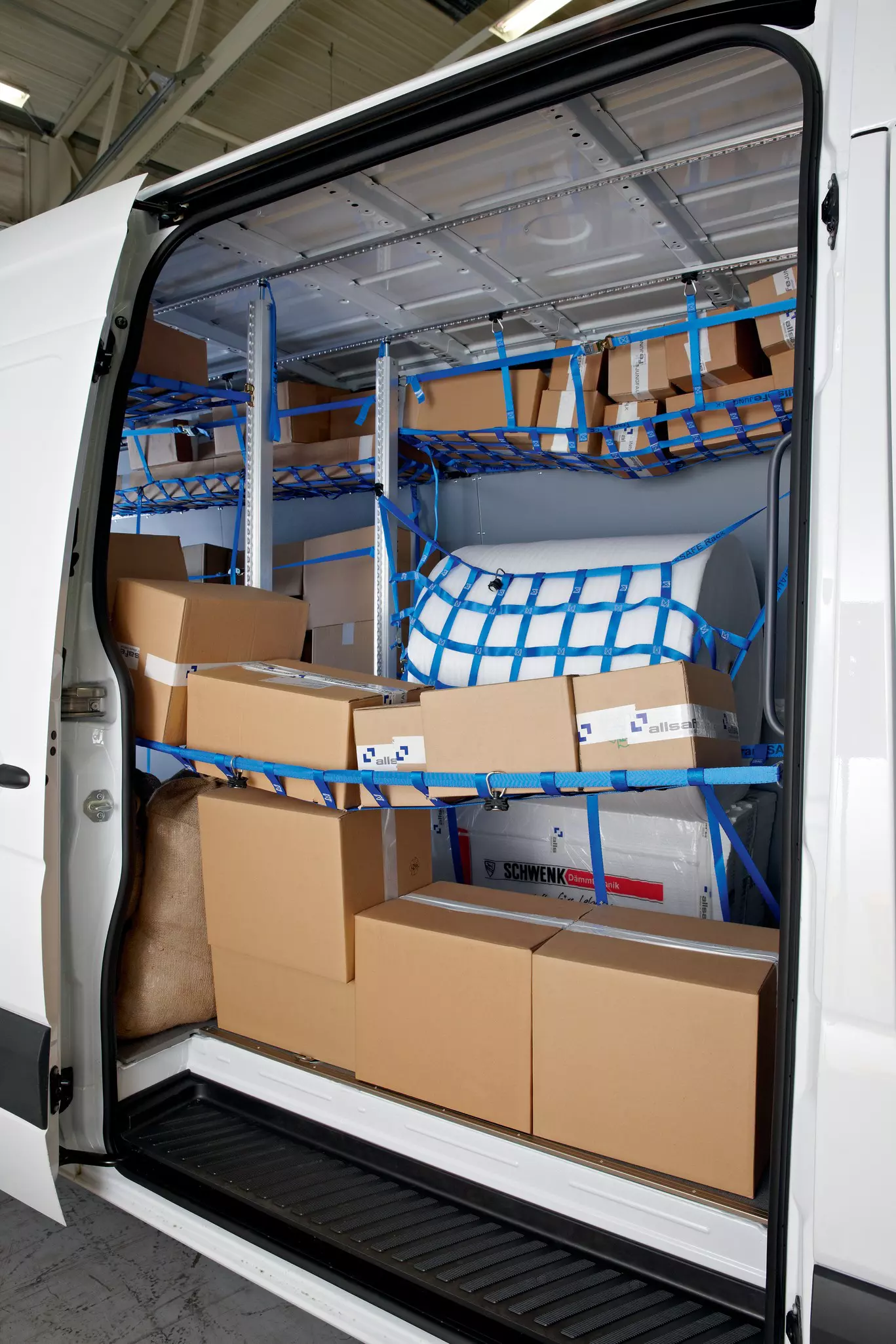 Voll beladener Transporter-Laderaum mit Kartons hinter blauen Sicherungsnetzen und Gurten