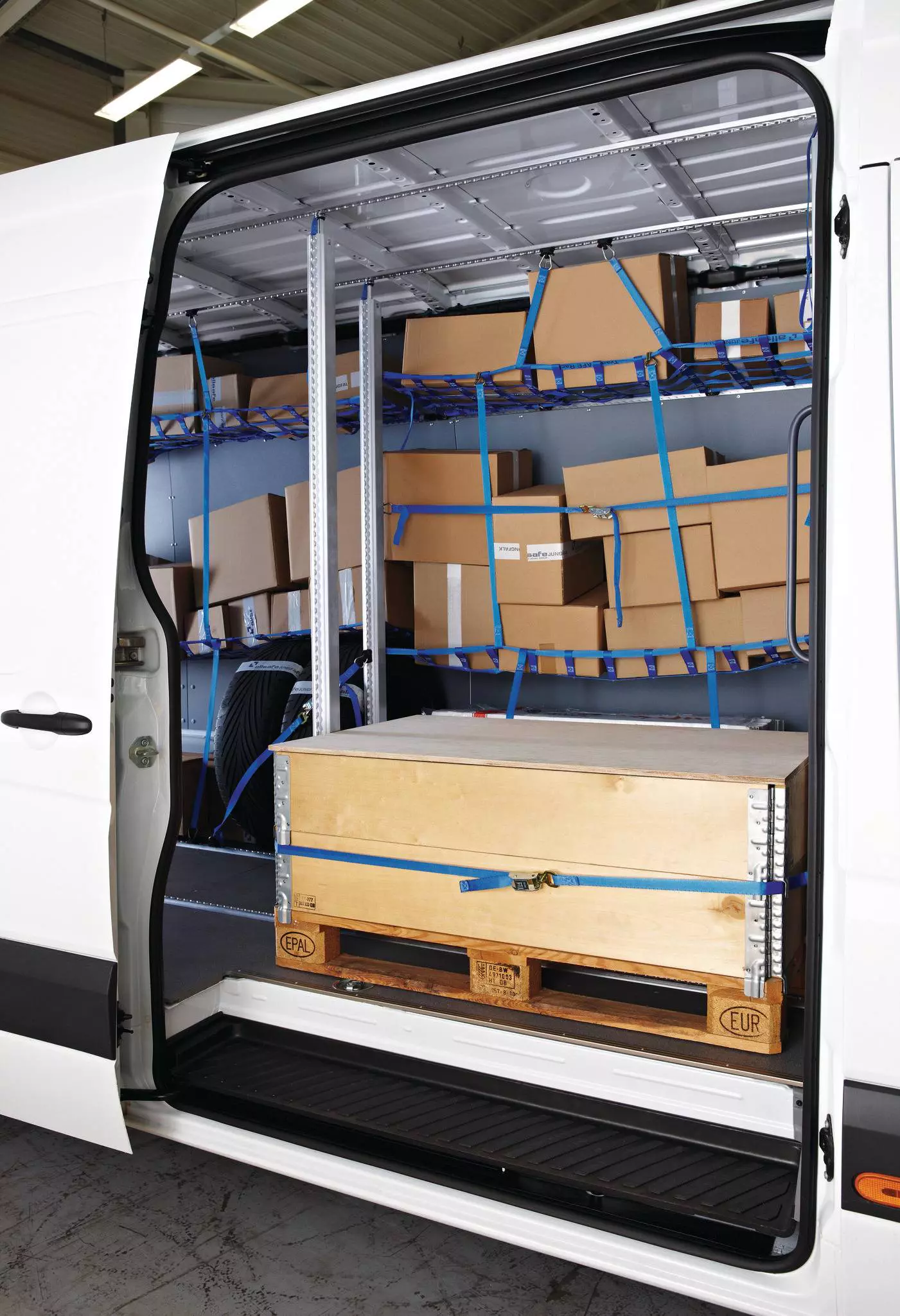 Transporter-Laderaum mit Holzkiste auf Palette und darüberliegenden Netzregalen voller Kartons